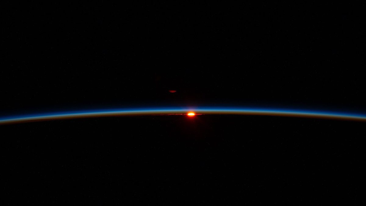 Los primeros rayos de un amanecer orbital iluminan las capas de la atmósfera, justo por encima de las cuales vuela.